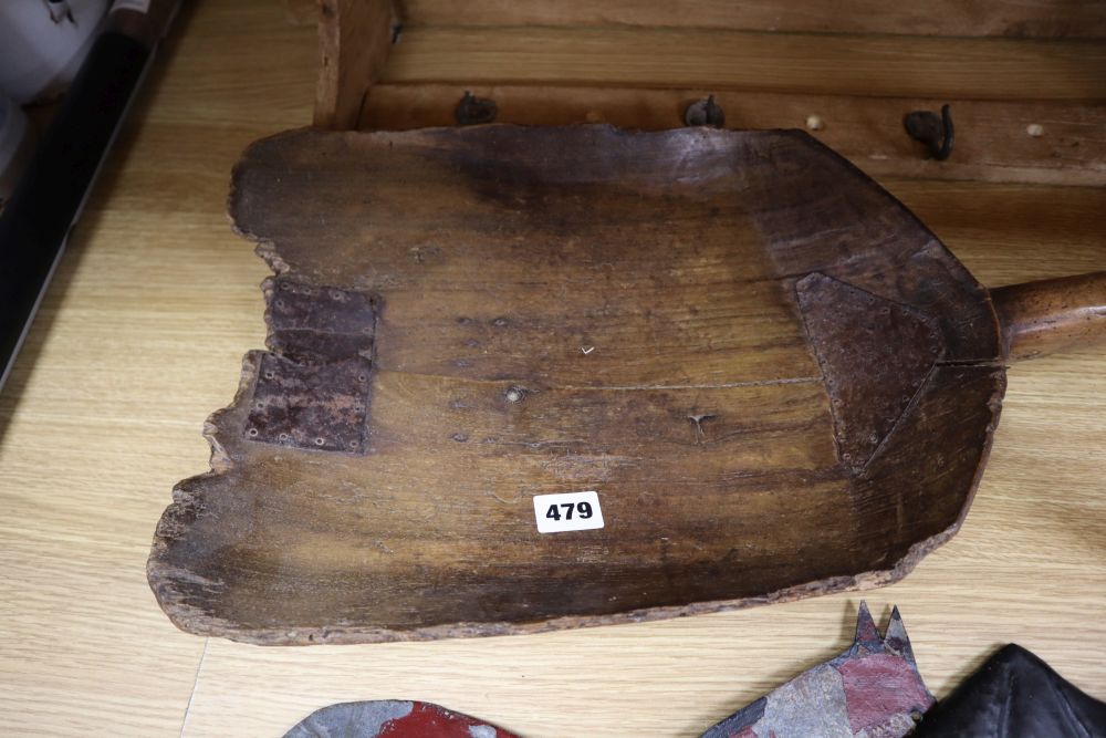 A 19th century sycamore grain shovel, 98cm., a beech wall shelf and two painted sheet metal ornaments
